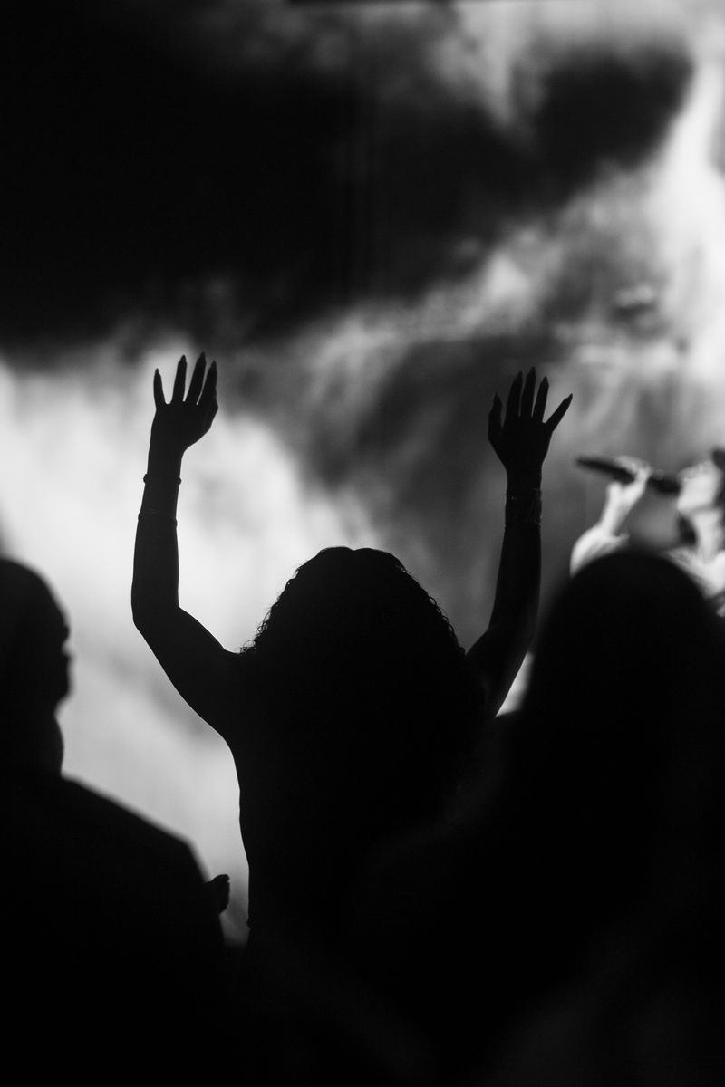 Raised hands silhouetted against stage haze