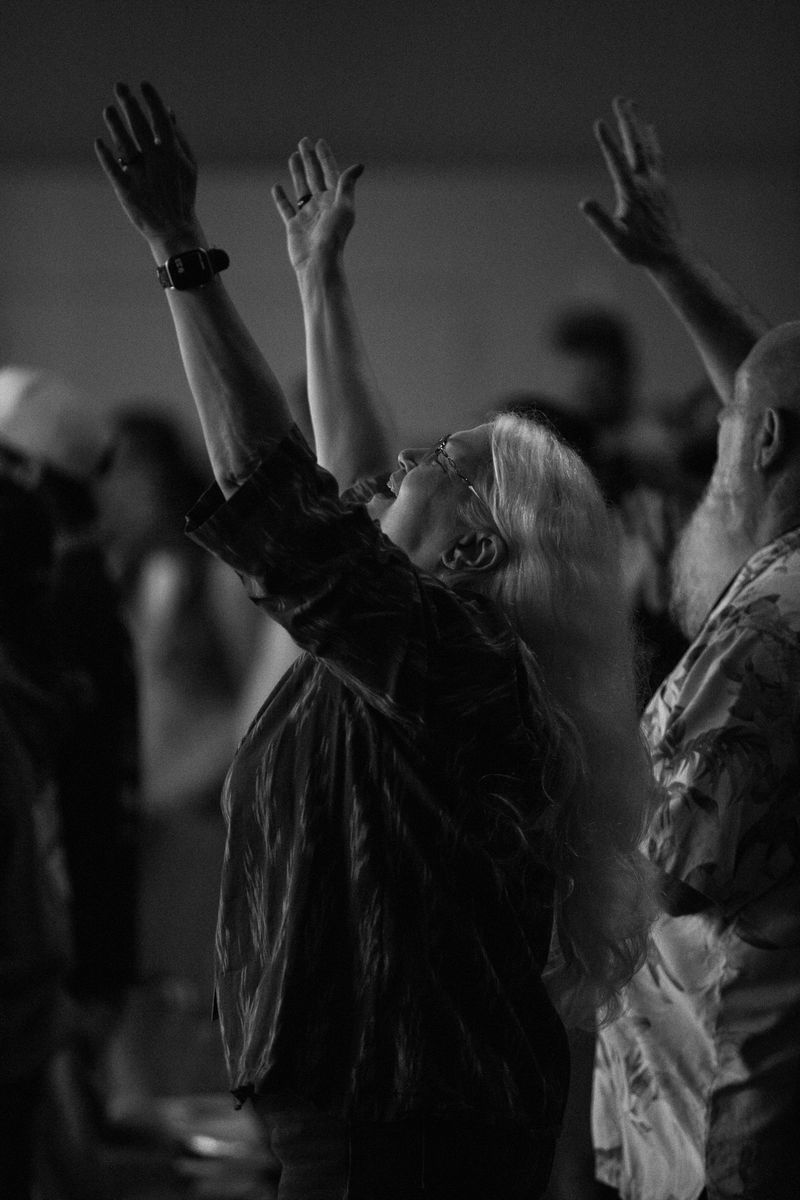 A woman with both arms lifted during worship
