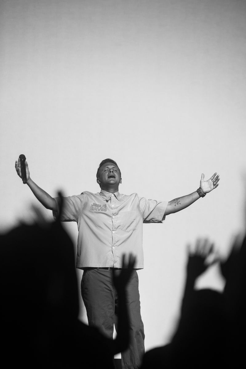 A man standing with his arms open wide in worship