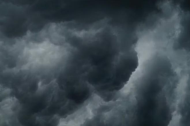An image of dark clouds against the night sky, with streaks of white light throughout.