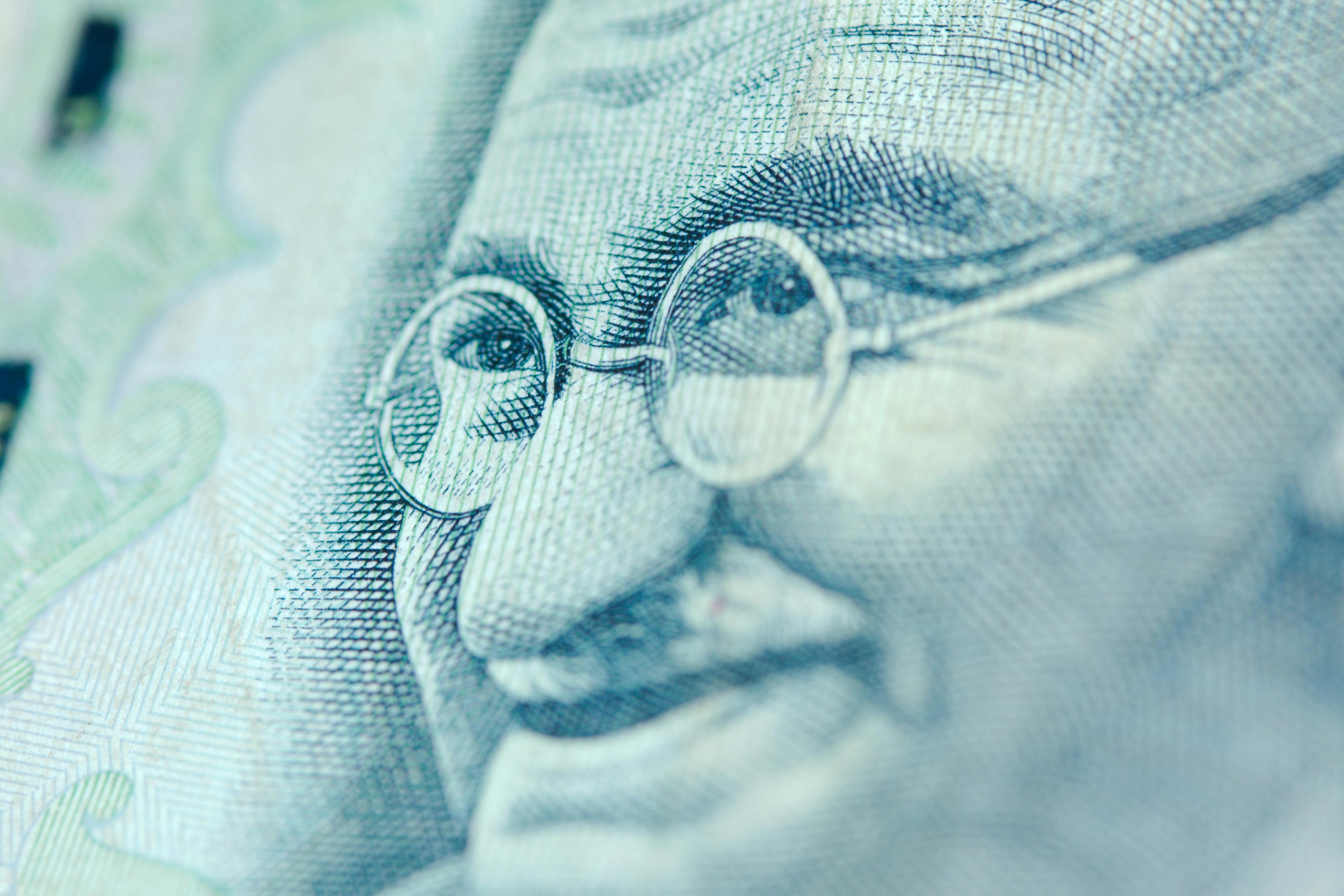 A scan of Gandhi's face on a bank note. The paper appears light blue.