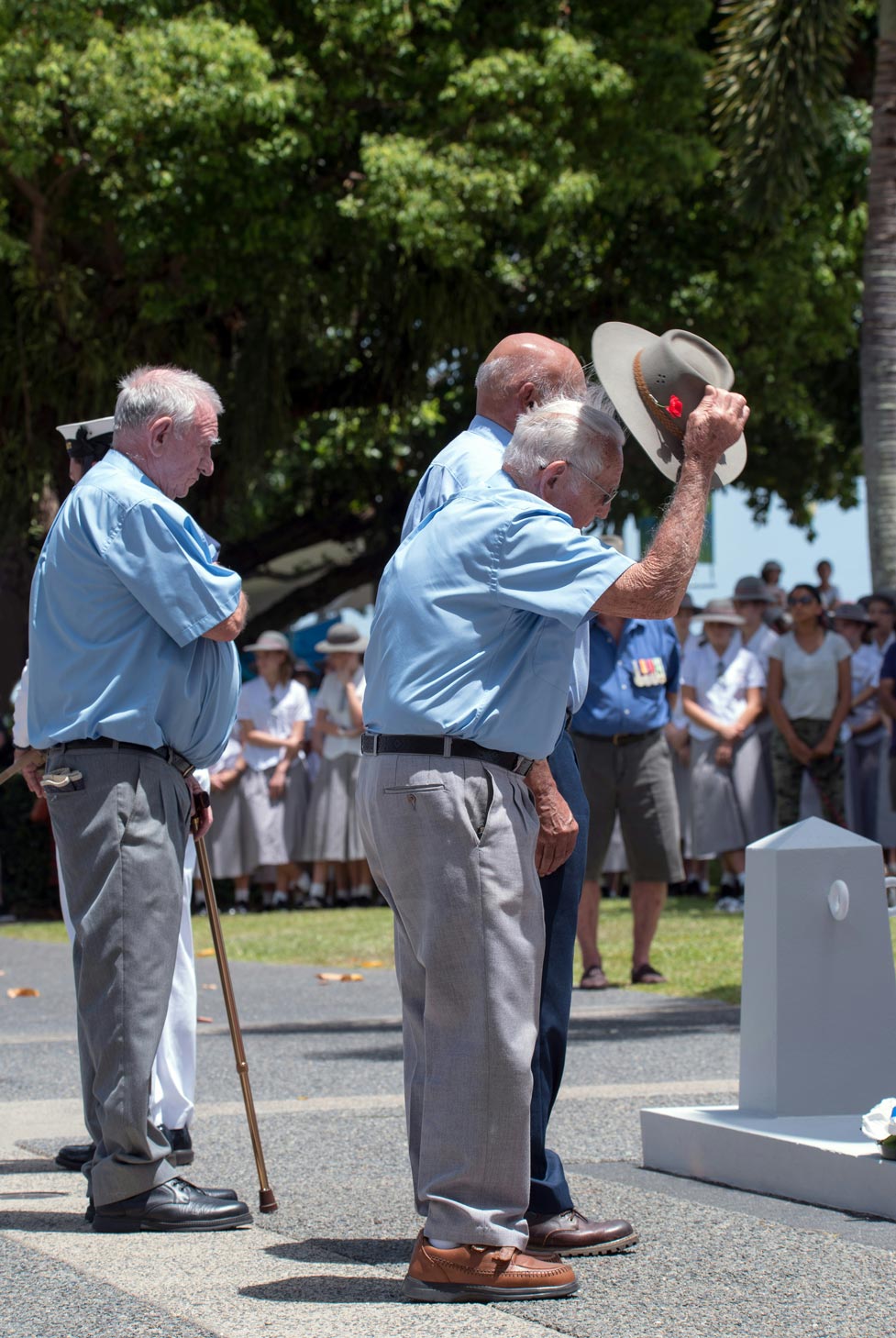 An image of veterans taking off their hats at a ceremonial remembrance event.