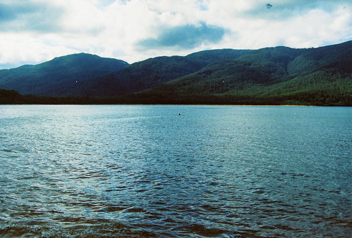An image of a river underneath large green rolling hills.