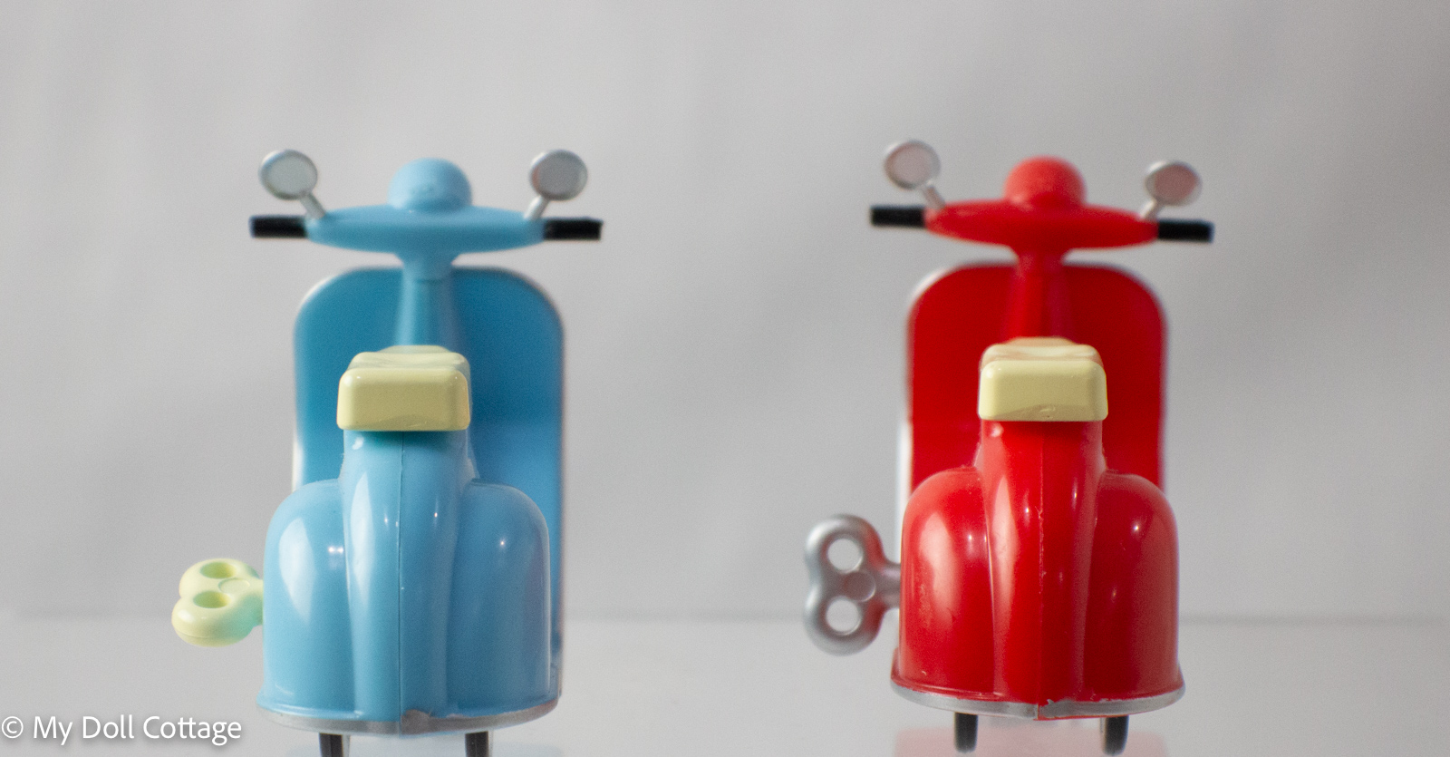 Rear view of red and blue 1980s wind-up mopeds showing wind-up keys