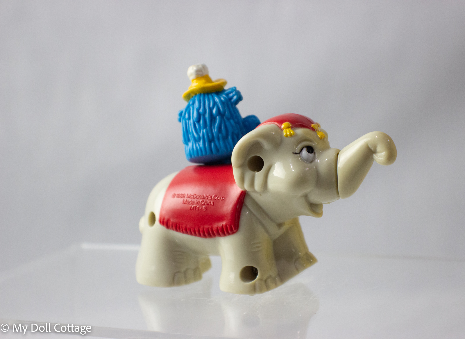 Side view of cream elephant toy with Fry Guy character on red McDonald’s blanket.