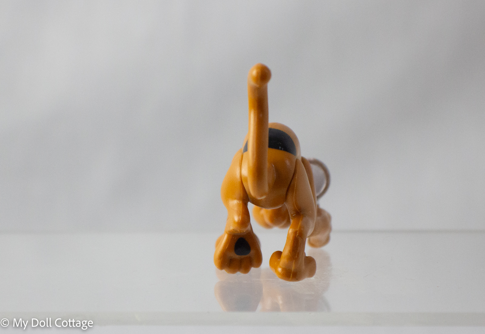Back view of Scooby-Doo Mystery Mates toy, showing raised tail and black spot markings, photographed on white background.