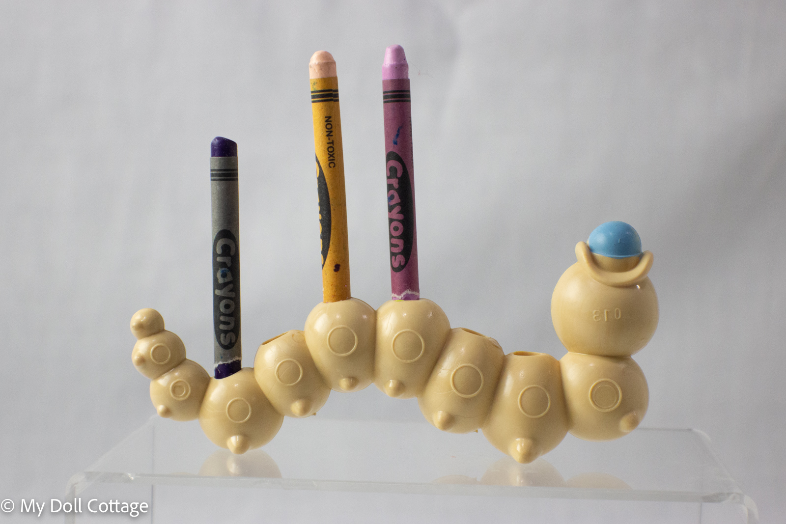 Rear view of caterpillar crayon holder with six crayon slots visible, holding three crayons.