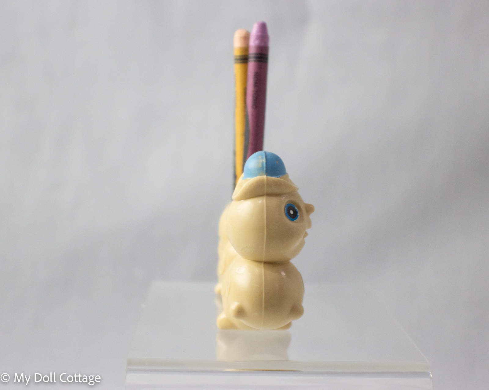 Side view of caterpillar crayon holder showing its smiling face and blue hat.