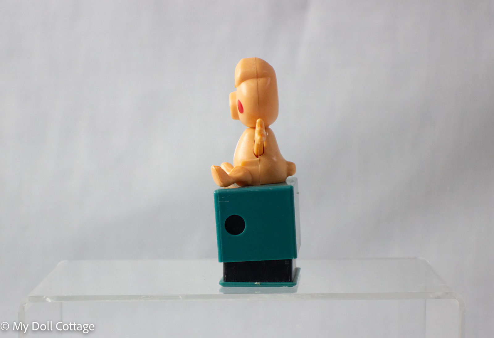 Side angle of pig pencil sharpener showing waving arm mechanism