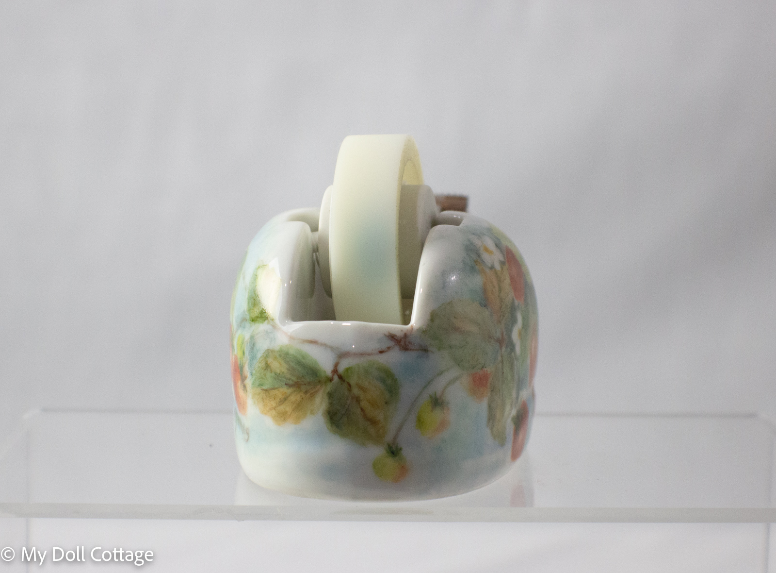Rear view of ceramic tape dispenser with strawberry and leaf design, tape roll visible.