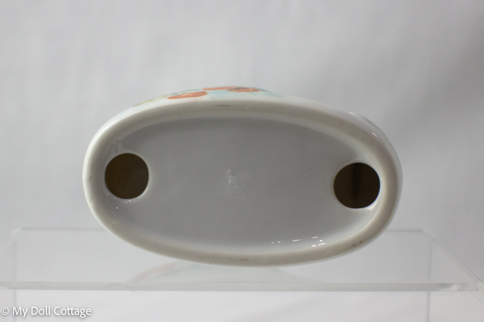Base view of ceramic strawberry tape holder showing plain white underside with two round holes.