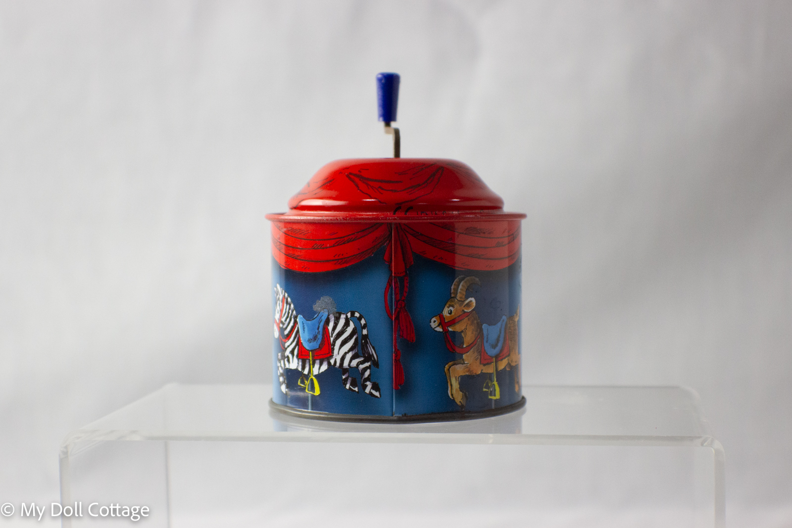 Front view of 1950s German tin barrel chime toy with red top and zebra and goat carousel animals