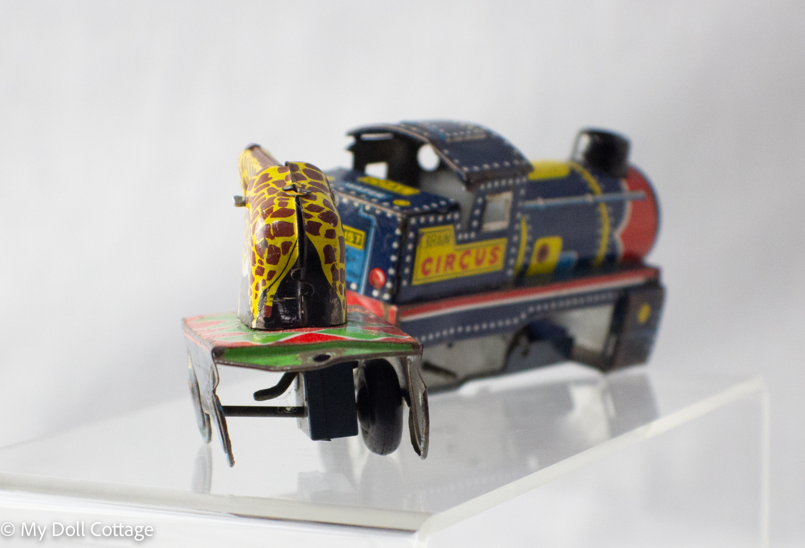 Close-up of giraffe carriage showing yellow giraffe figure on red and green lithographed base.