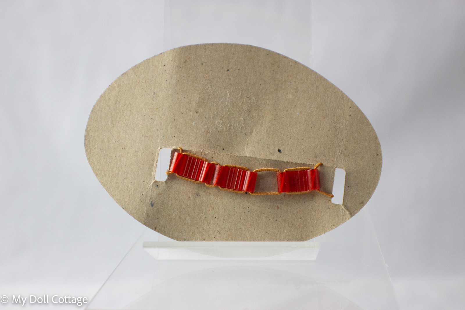 – Rear view of card showing red plastic strap secured through backing slots.