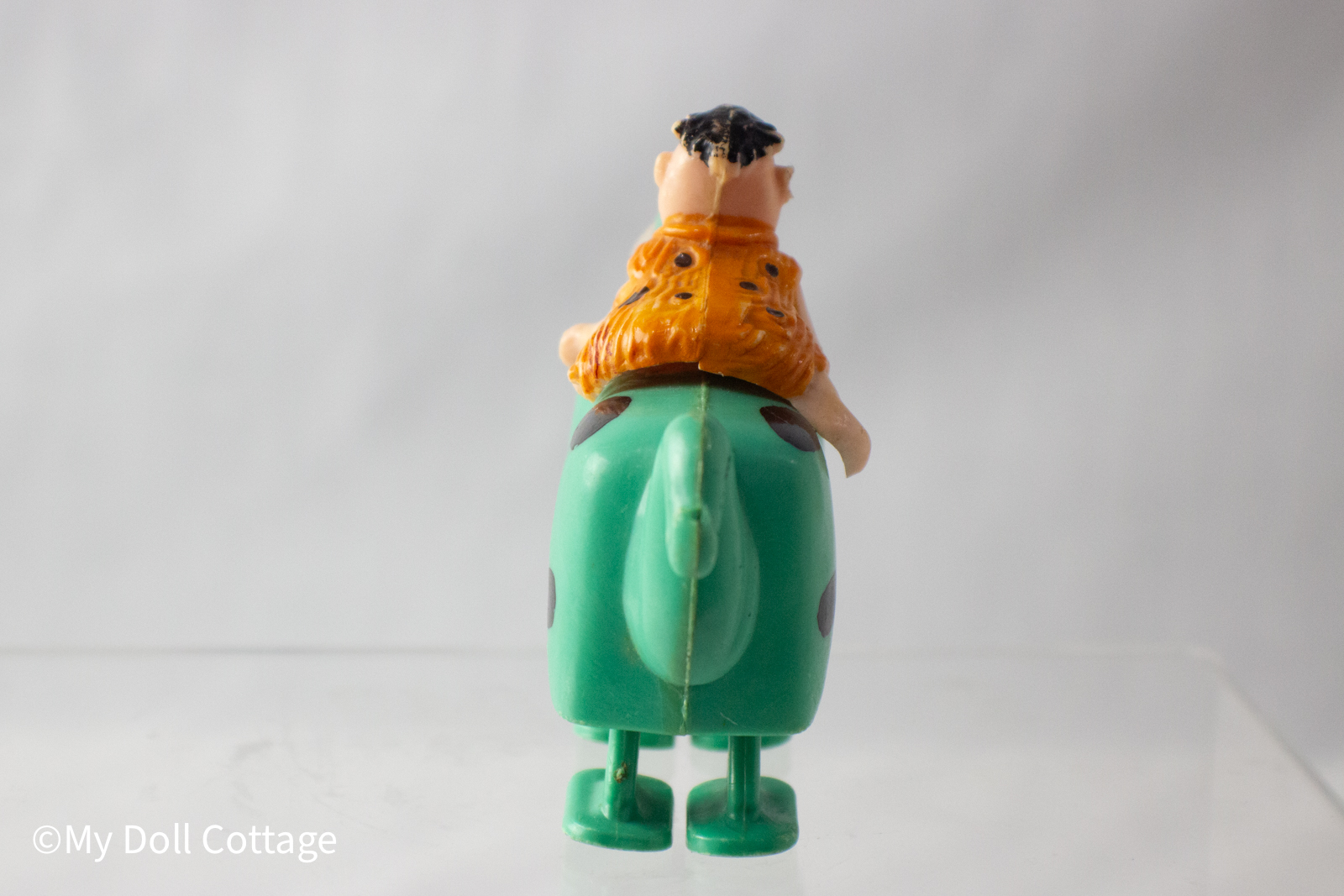 - Rear view highlighting dinosaur’s tail and Fred’s orange tunic.