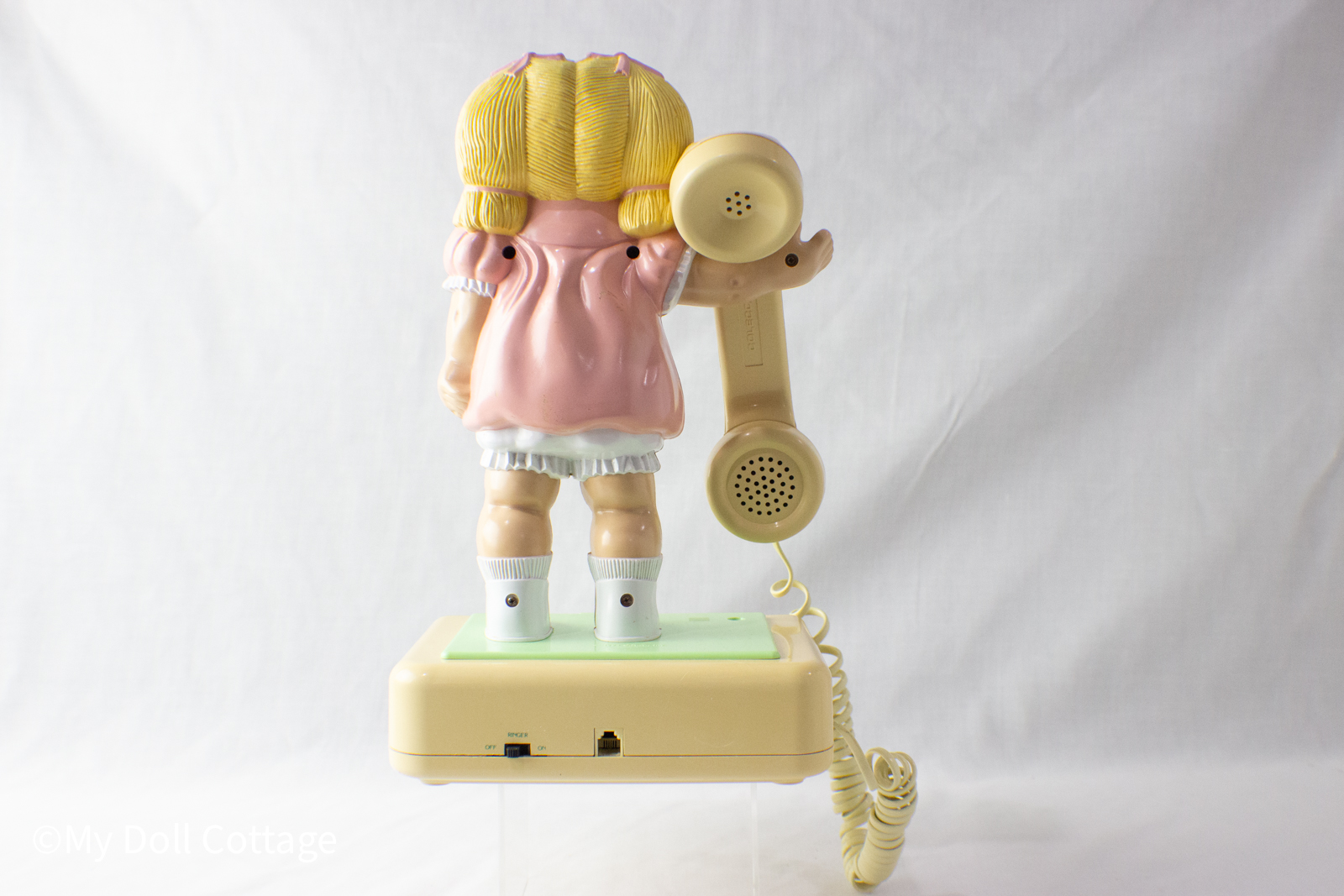 Rear view showing back of doll, hair detailing, and cord connection.