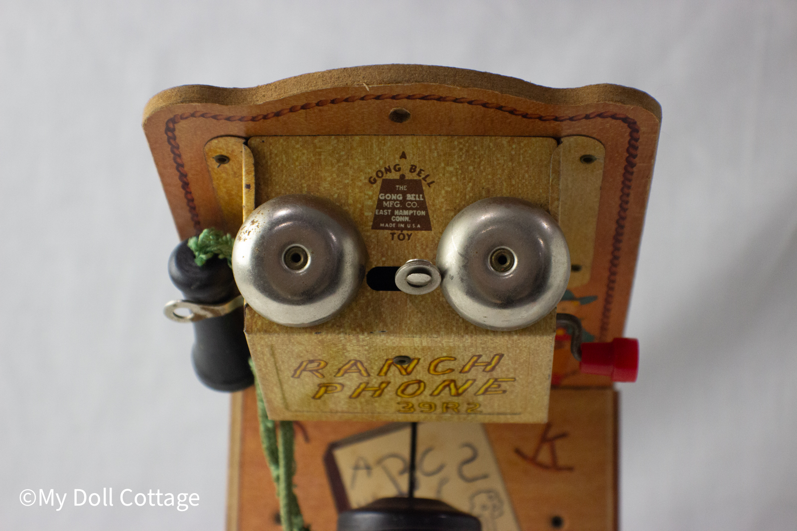 Close-up of the bells and gold plate marked “Ranch Phone 39R2,” with visible play wear.