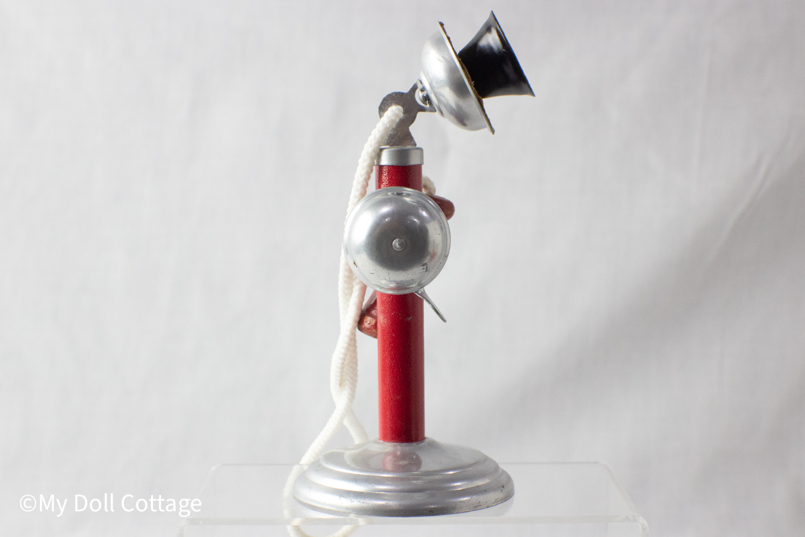 Left side profile of toy candlestick telephone showing wooden receiver and metal bell.