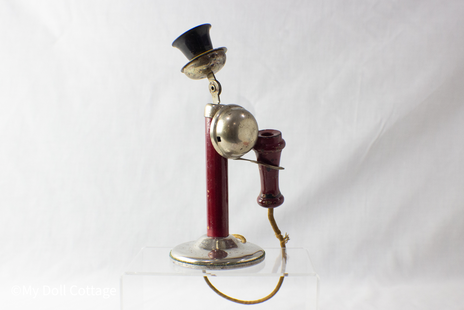 - Side view of the Gong Bell Playphone candlestick toy showing the bell mechanism and frayed yellowed cord.