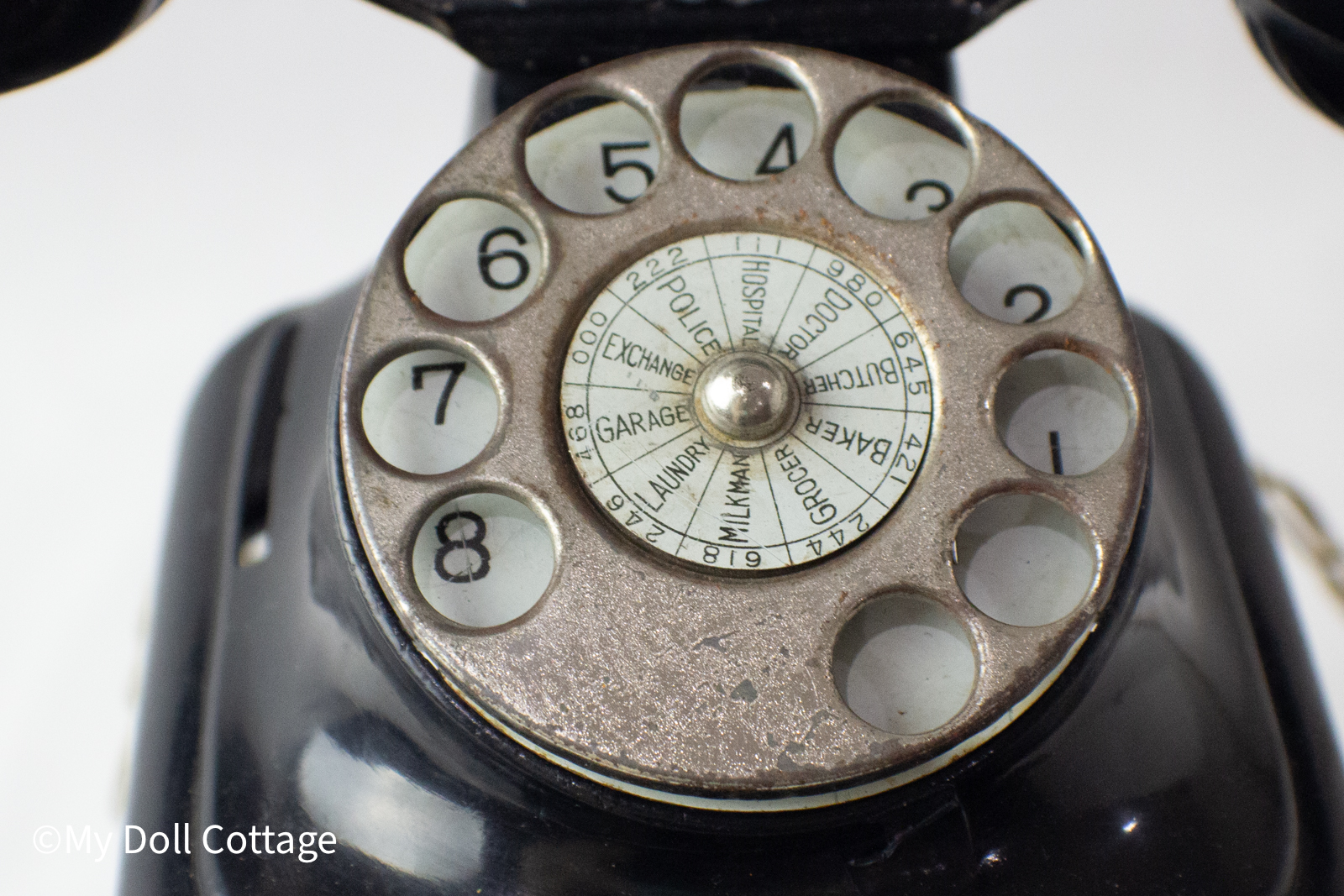 Front close-up of metal rotary dial with printed service numbers such as Police, Garage, and Doctor.