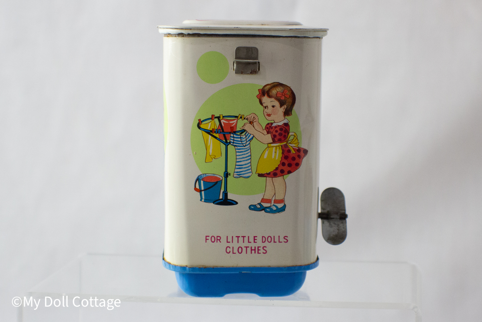 8.	Side panel illustration of a girl hanging doll clothes on a rack with the text “For Little Dolls Clothes”.