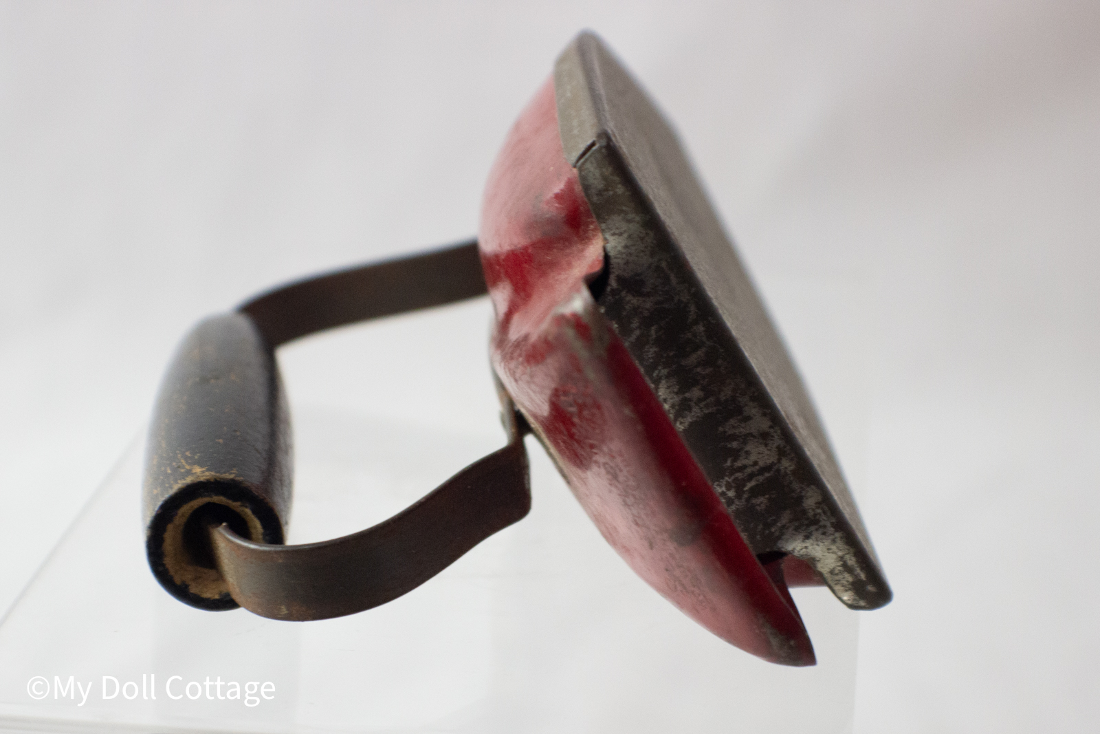 Back view of toy iron with black wooden handle and visible wear. 