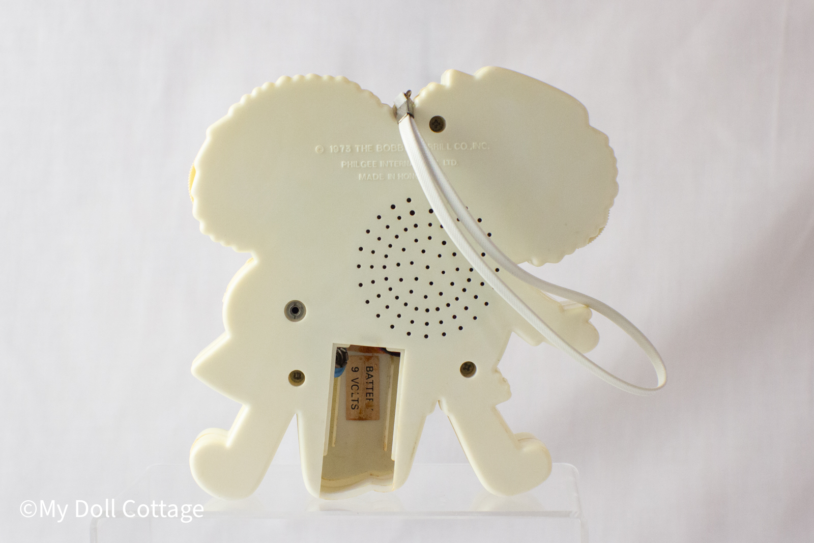 Rear view of the transistor radio showing stamped marks ©1973 The Bobbs-Merrill Co., Inc. and Philgee International Ltd., with speaker holes and damaged battery compartment.