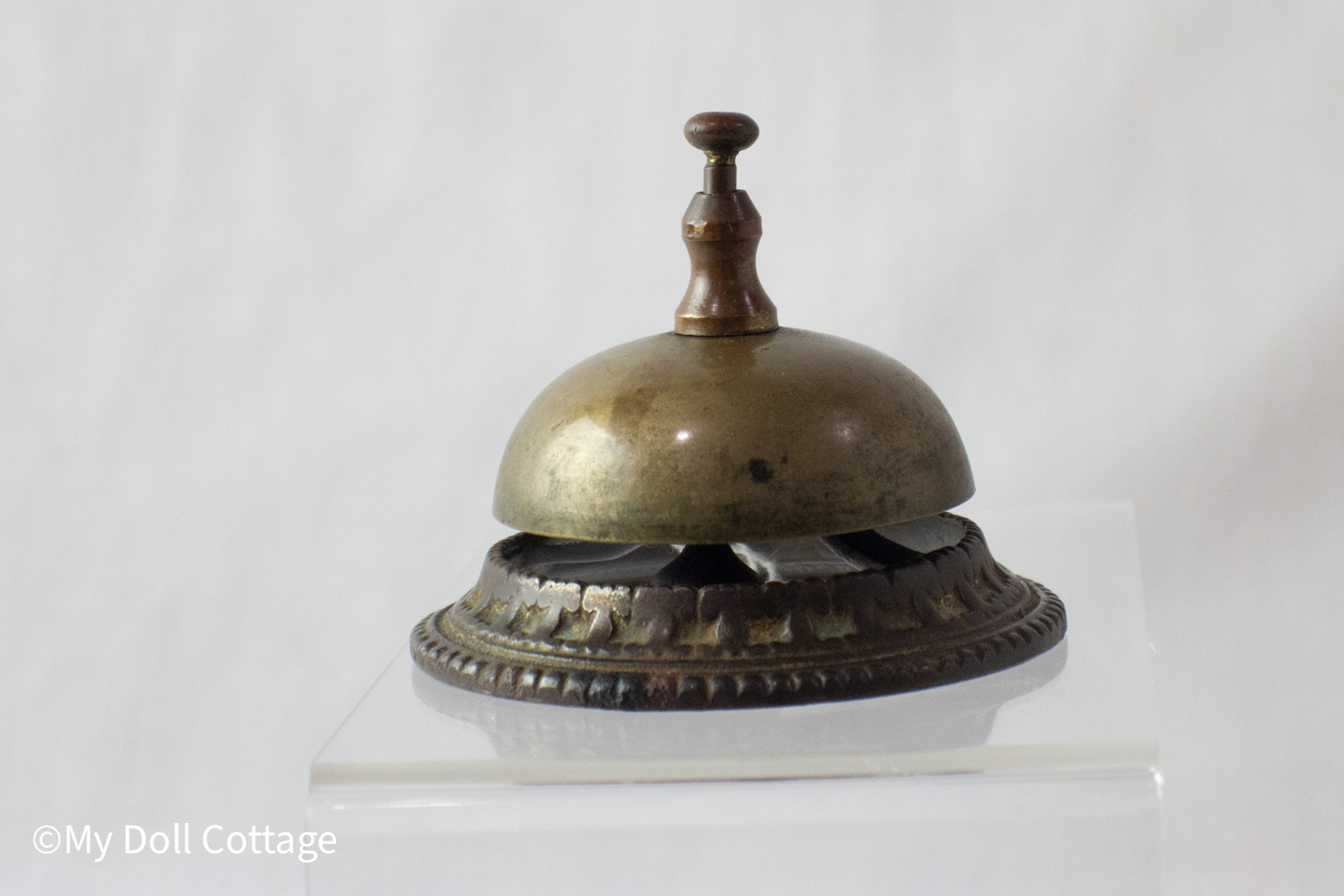 Side view of bell showing raised base design and aged brass dome.