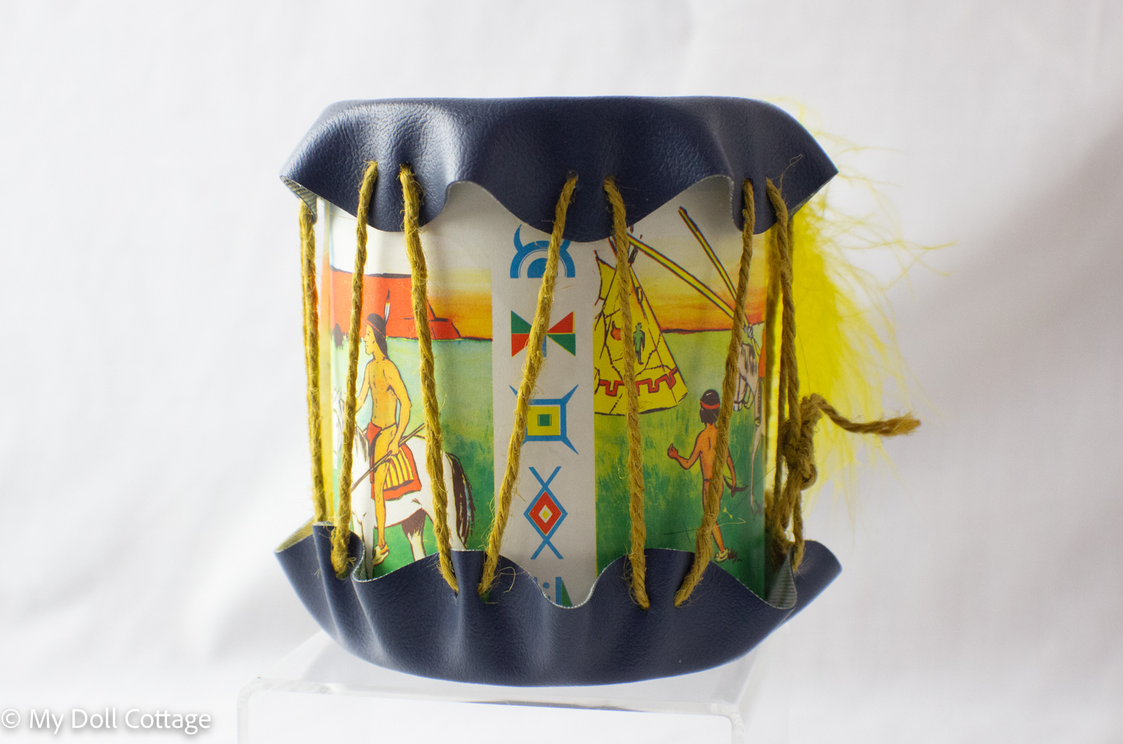 Side view of Canadian souvenir drum showing printed Indigenous-inspired figures, tipis, and geometric motifs with twine lacing.