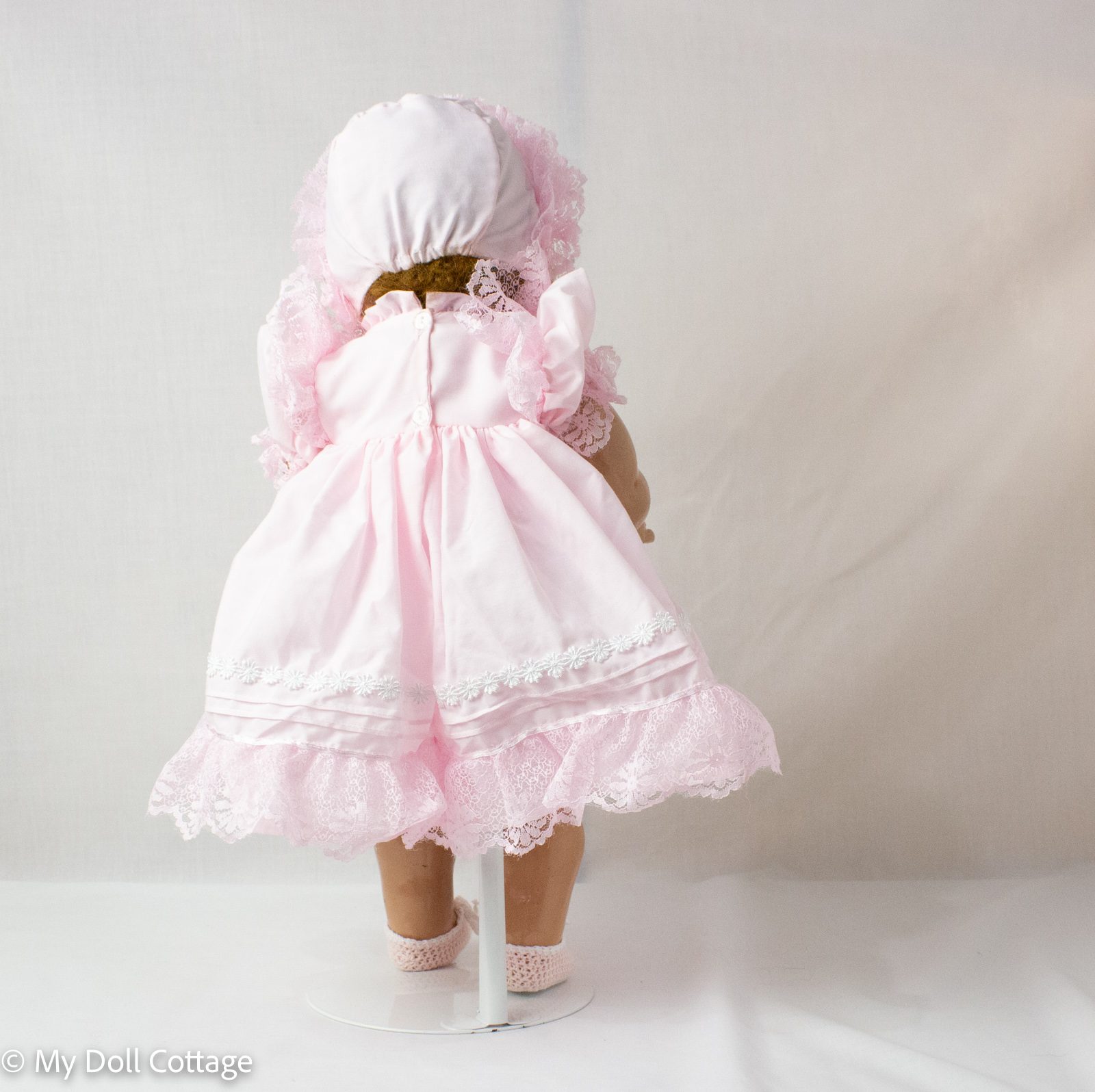 Rear view of doll showing dress closure and bonnet
