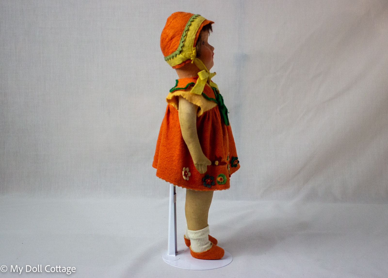 Side full-length profile view of doll showing felt shoes, socks, and bonnet styling.