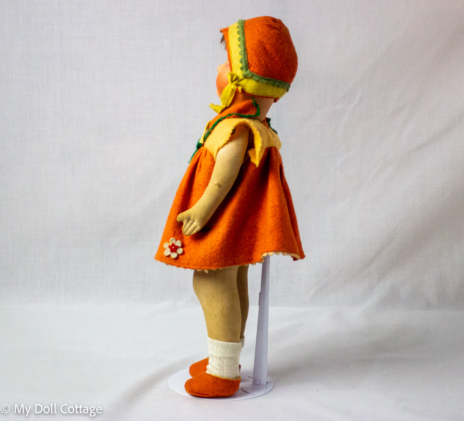 Side full-length profile view of doll showing felt shoes, socks, and bonnet styling.