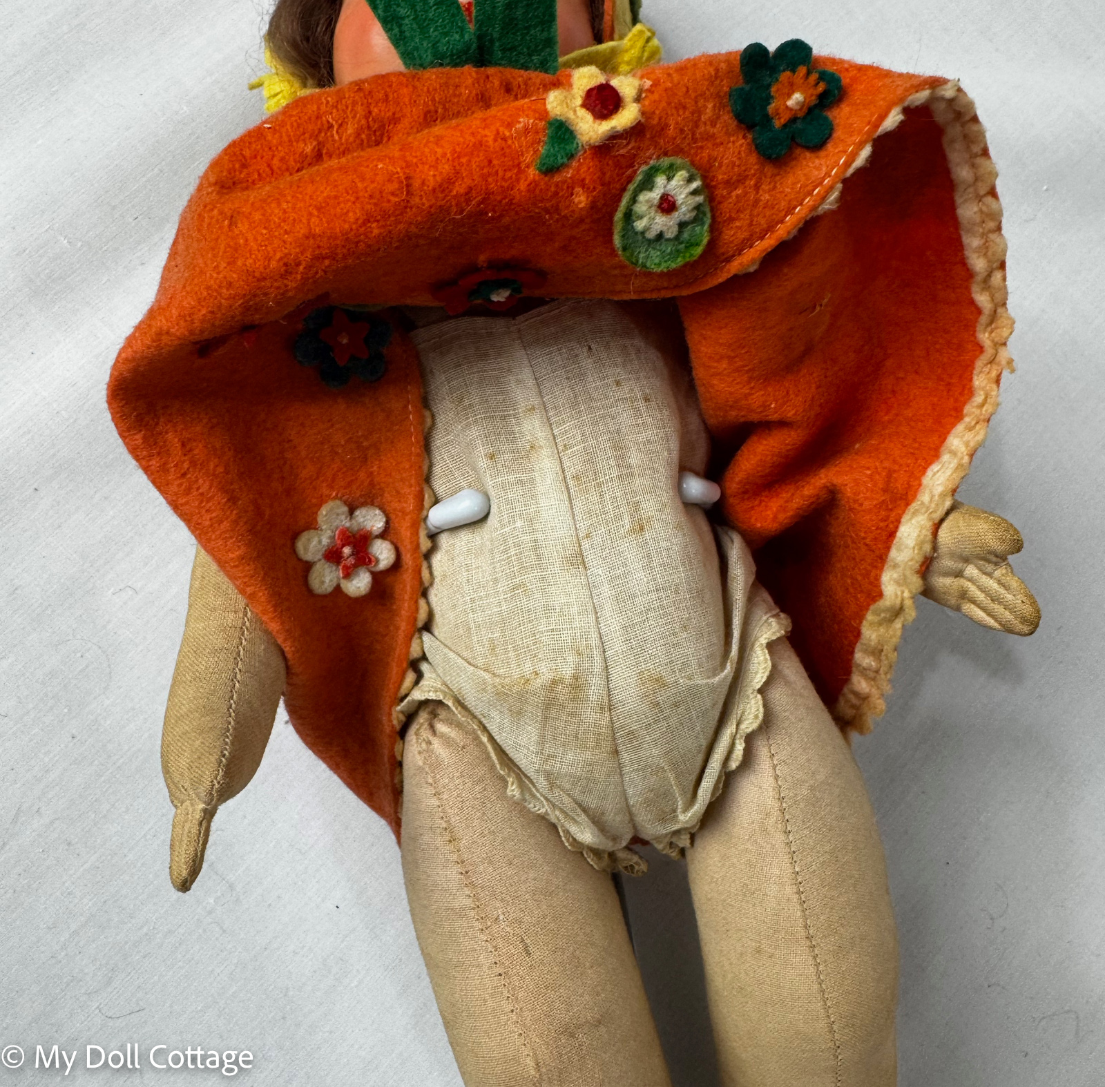 Interior view beneath orange felt dress showing original cloth torso construction and undergarments.