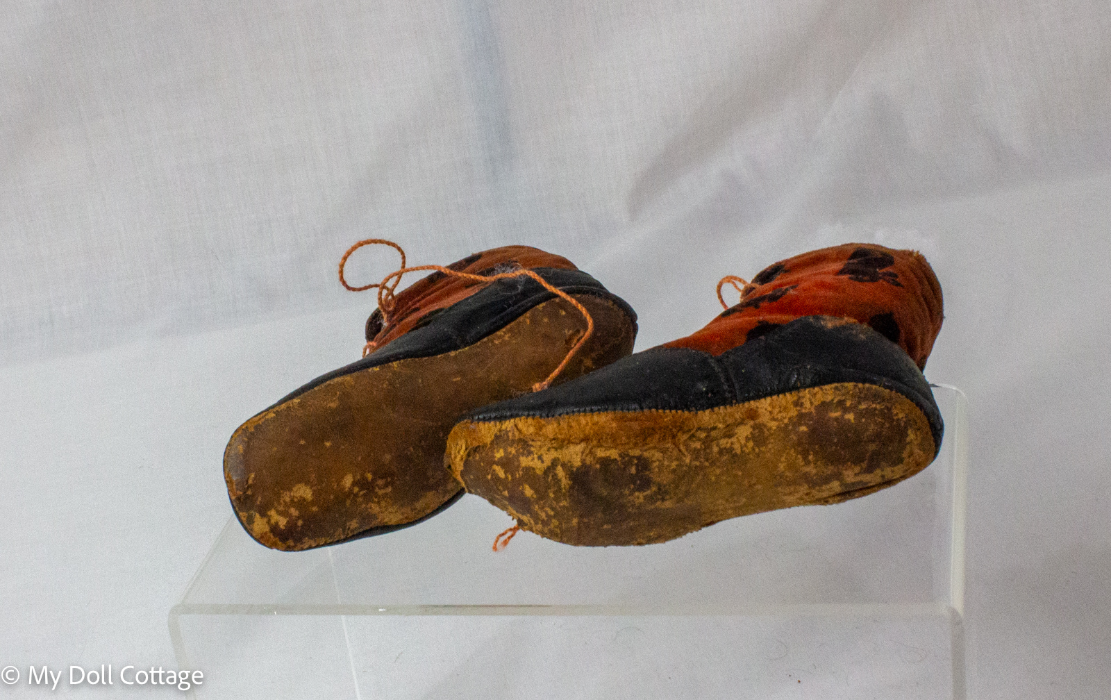 Pair of antique child’s lace-up boots with black leather lowers and red velvet uppers featuring bunny motifs displayed from front angle.
