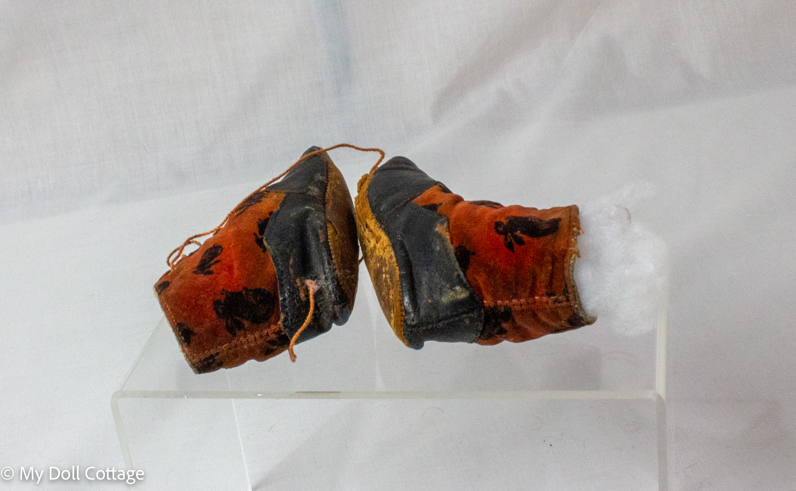 Pair of antique child’s lace-up boots with black leather lowers and red velvet uppers featuring bunny motifs displayed from front angle.