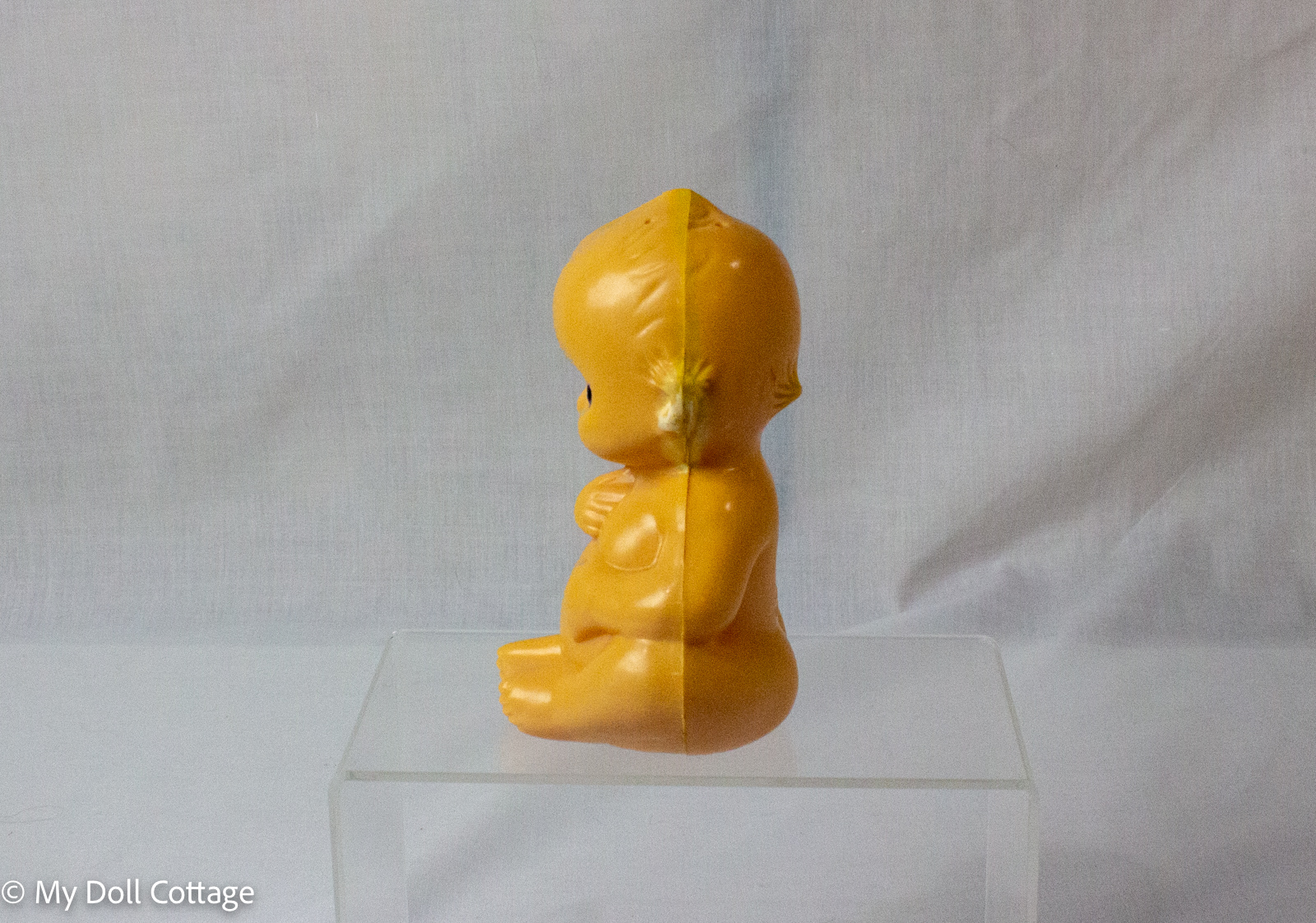 2. Side profile of peach-coloured Kewpie powder shaker showing mould seam and seated body shape.