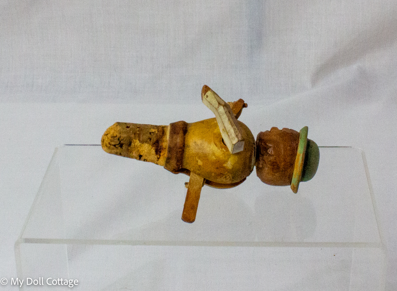 2. Side view of vintage Italian folk art bottle cork showing carved wooden arms and rounded body.