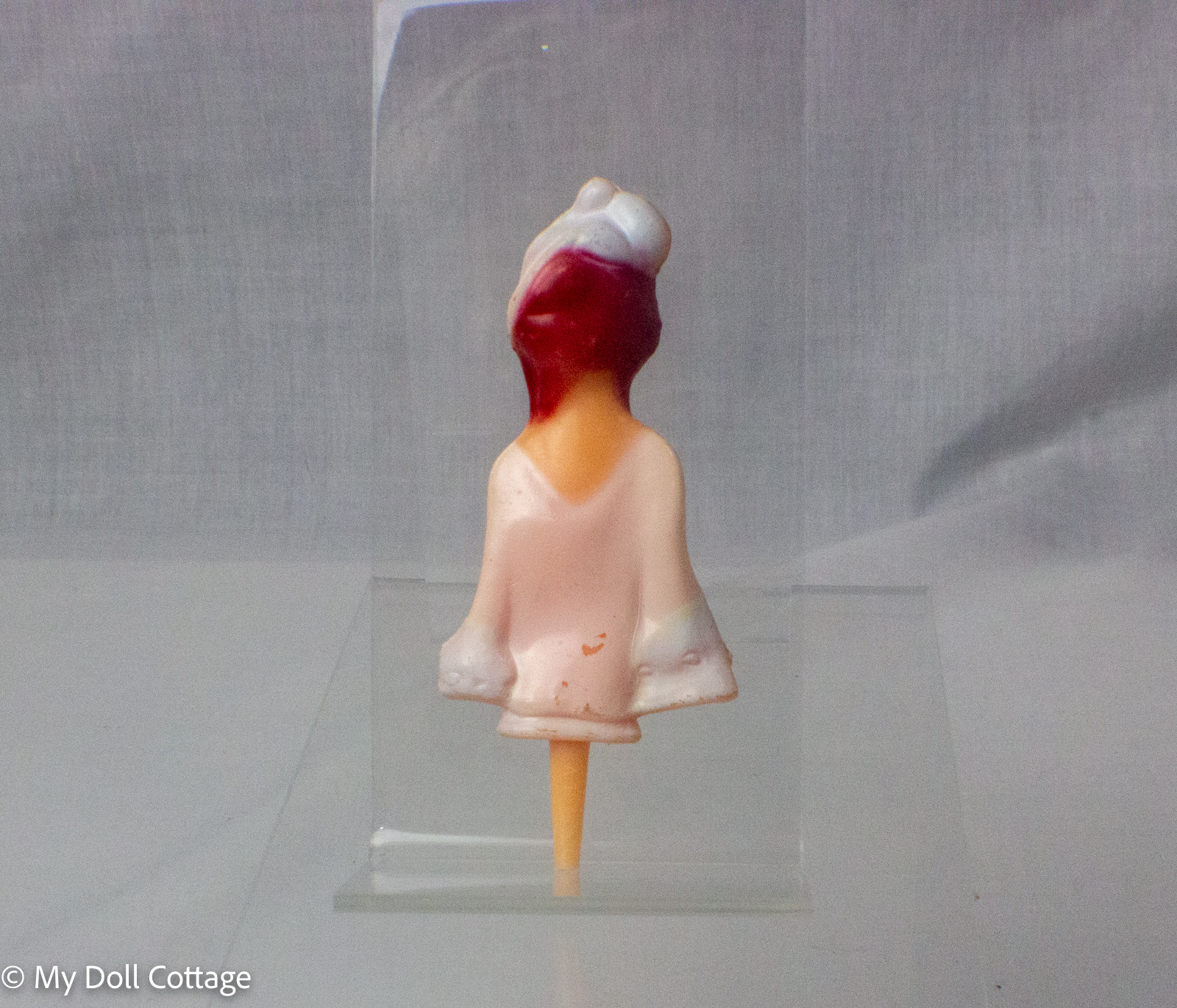 3. Rear view of vintage hard plastic bottle stopper showing red hair and flowing white garment.