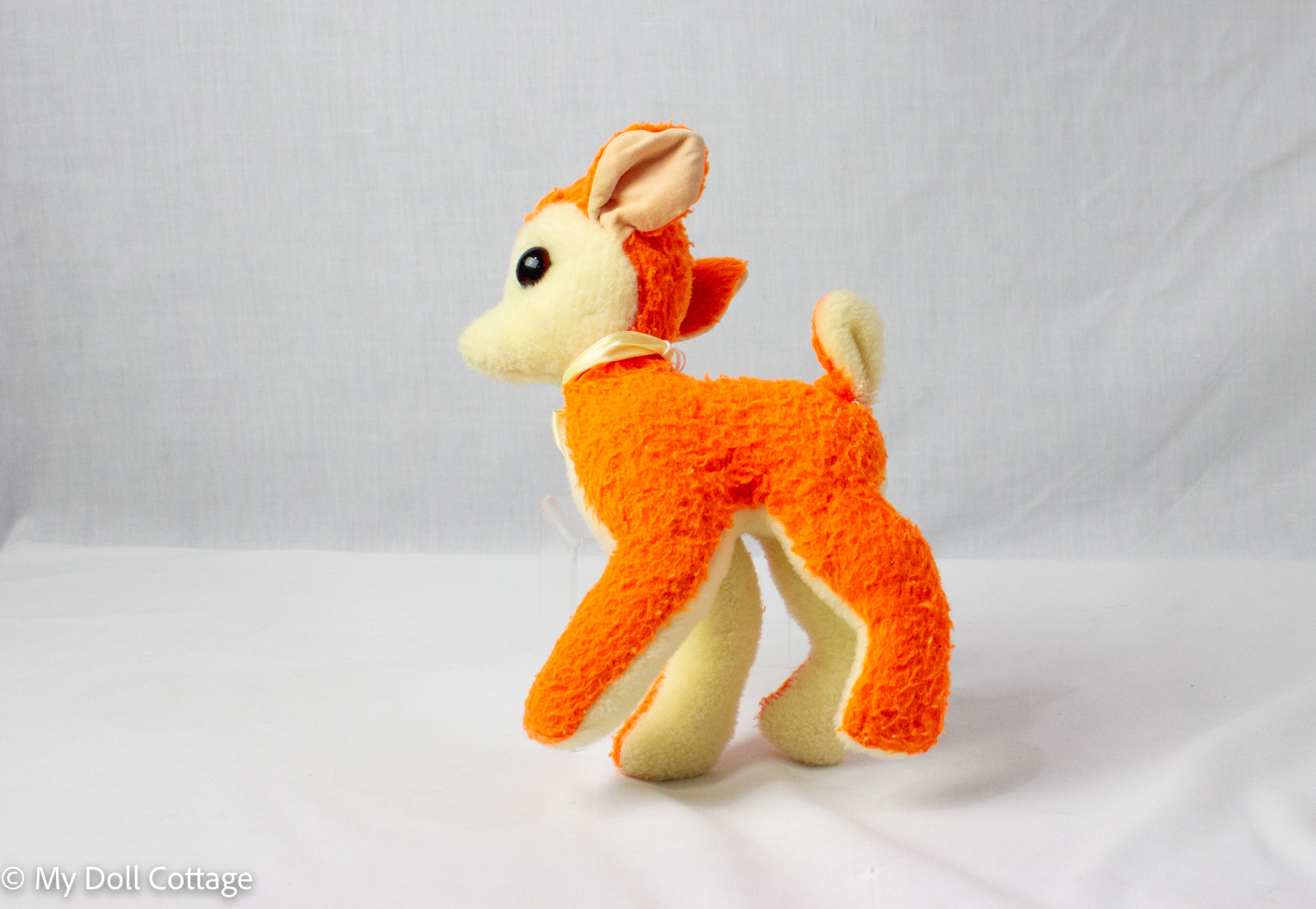 Side profile of orange plush reindeer with ribbon