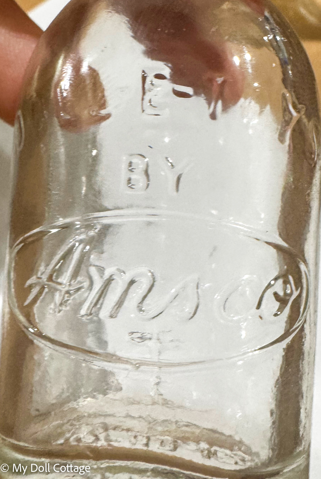 8. Close-up of embossed bottle measurements and maker markings on miniature glass bottle.