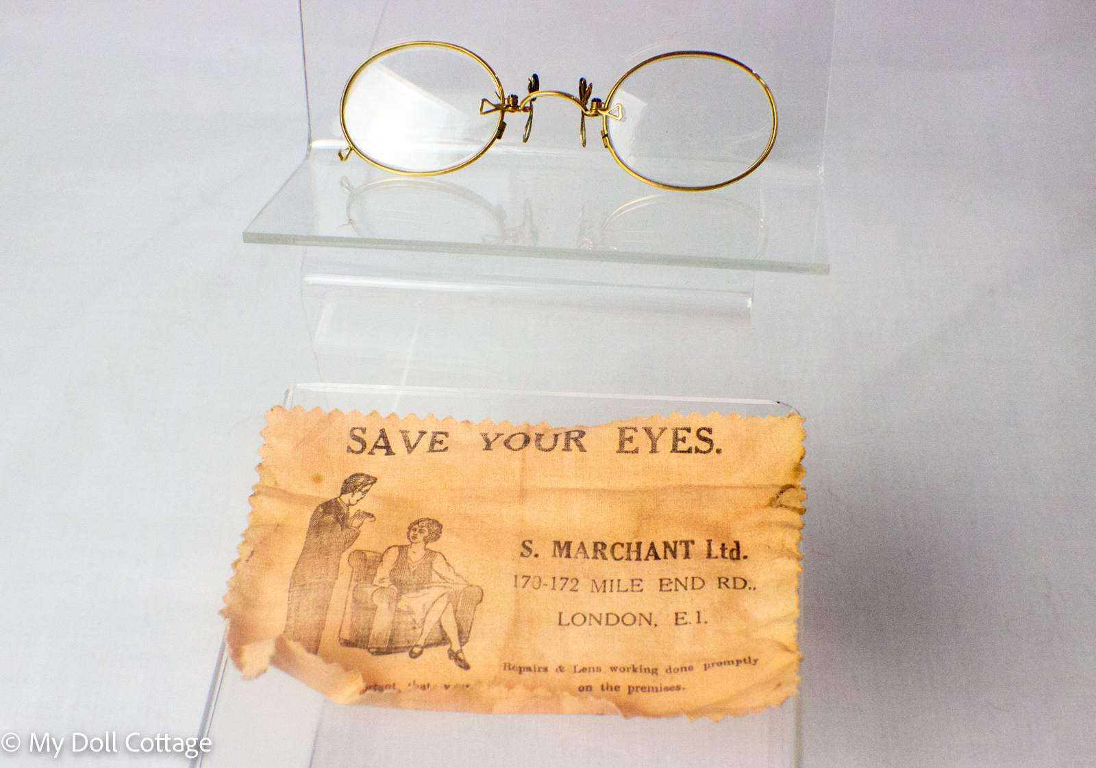 Front view of Edwardian 10ct rolled gold pince-nez spectacles displayed above the original S. Marchant Ltd London advertising cleaning cloth.
