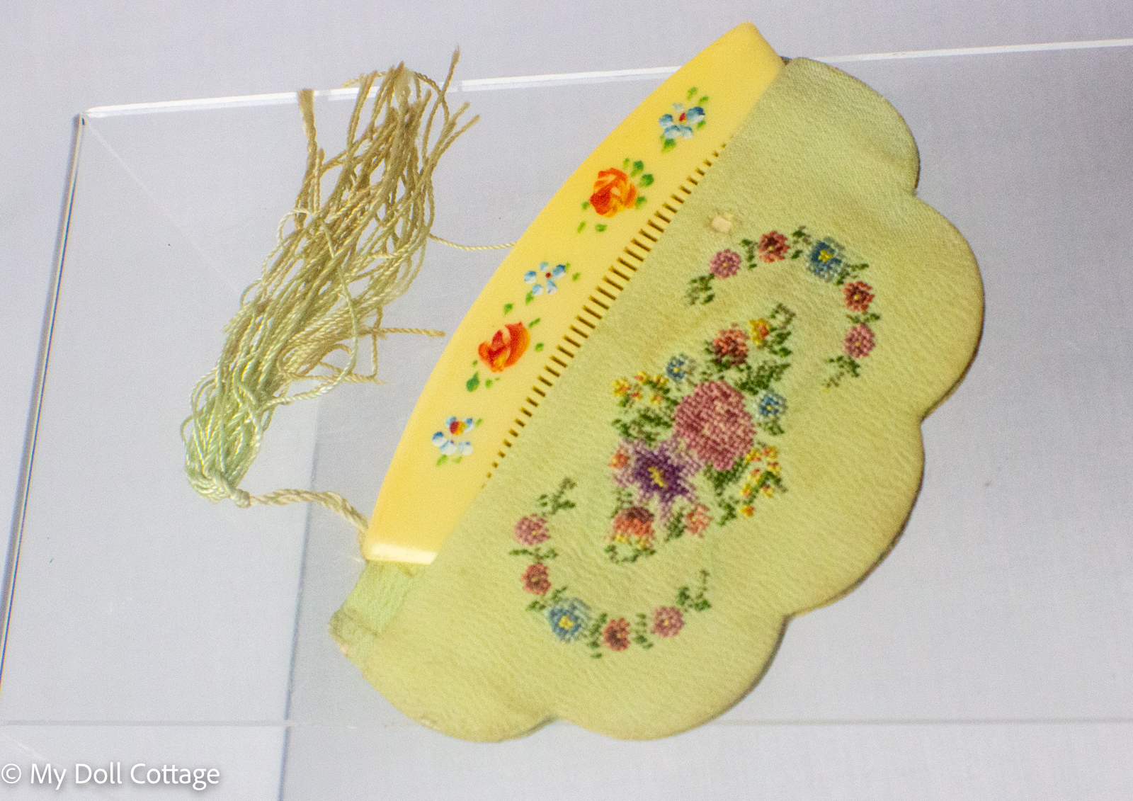 Purse comb with decorative tassel showing the floral celluloid comb and embroidered case.