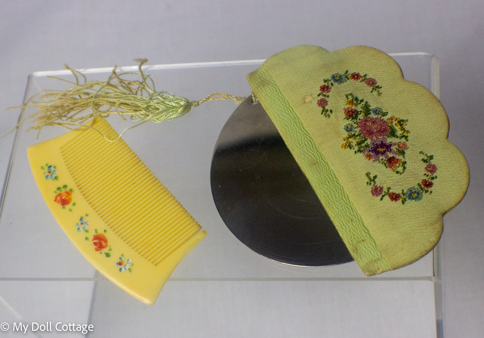 Front view of the ladies' purse comb beside its embroidered floral holder.