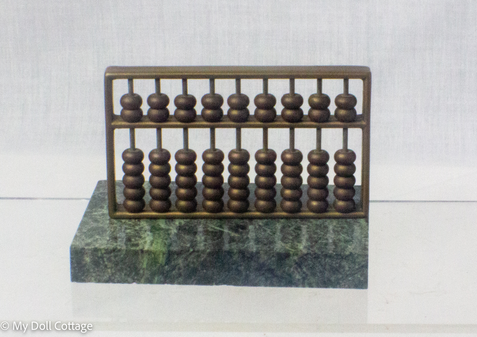 Early twentieth-century miniature all-brass abacus with ten rods and sliding brass beads in a rectangular brass frame.
