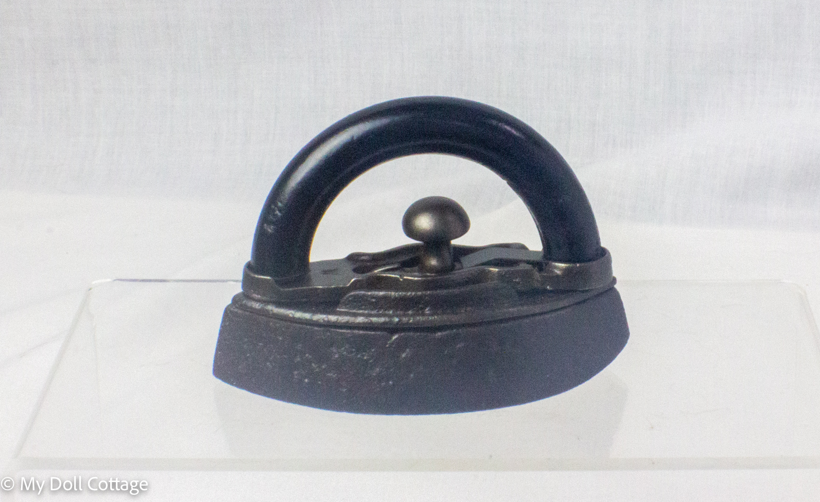 Side profile of the Mrs. Potts style miniature cold handle sad iron showing the detachable handle fitted to the cast iron body.