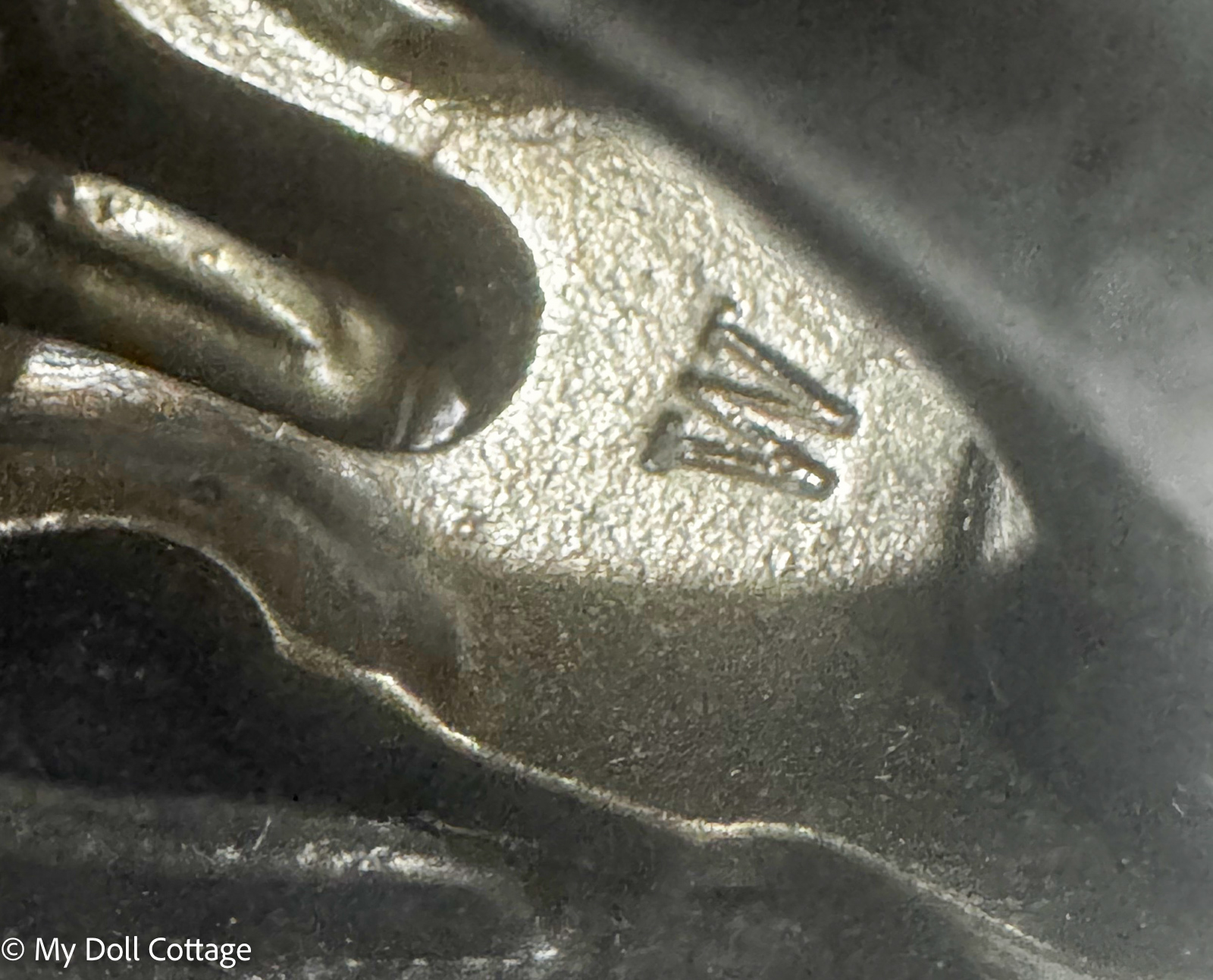 Close-up of the small stamped "W" foundry mark beneath the locking mechanism on the miniature salesman sample iron.