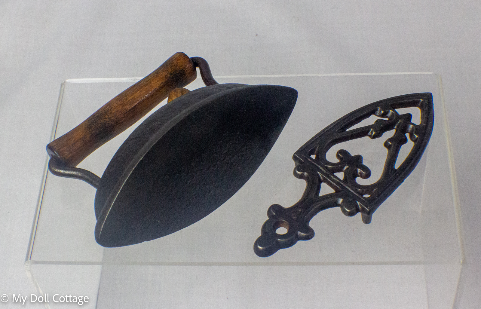 Underside view of the salesman sample iron displayed beside its decorative cast iron stand.