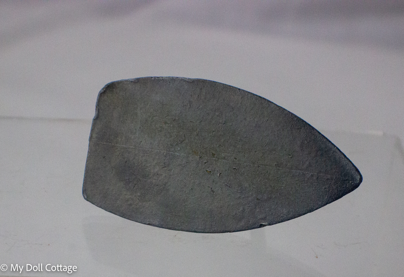 Underside view showing the plain alloy base of the miniature toy iron.