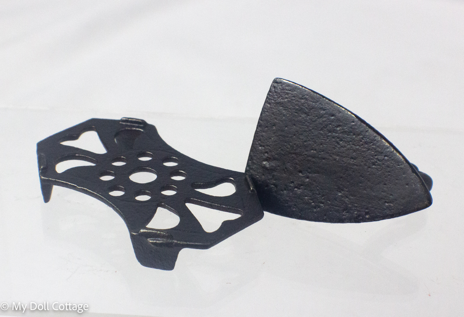 Opposite angled view highlighting the detailed cast handle and pierced trivet design. 