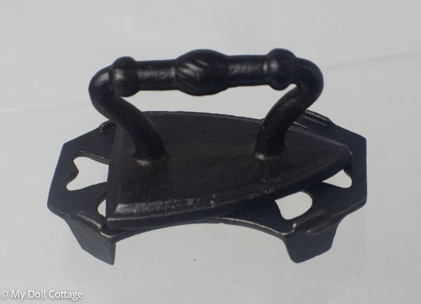 Angled view showing the turned handle and pierced cast iron trivet. 